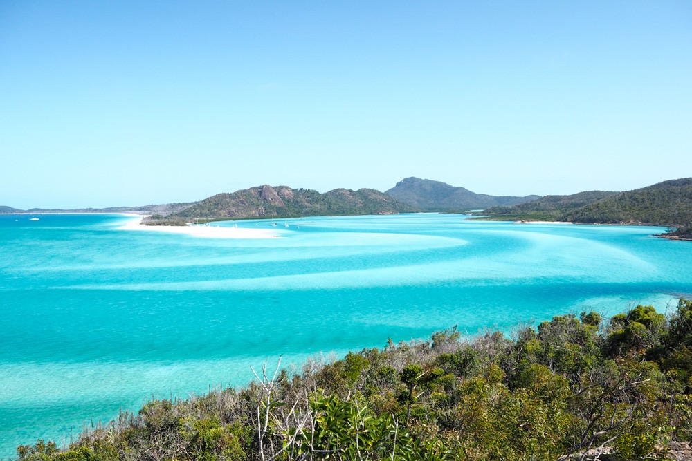 fotografía de las islas WhitSundays de Australia. Se ve el mar muy azul con agua cristalina y las montañas detrás